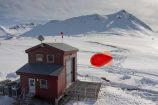 Ballonfüllhalle mit Fesselballon Die Atmosphärenforscher des Alfred-Wegener-Instituts nennen ihn „Miss Piggy“: Der rote Fesselballon kommt regelmäßig in mehrwöchigen Messkampagnen zum Einsatz. An einem 1,5 Kilometer Seil können Forscher mehrere Sonden in Reihe anbringen oder nacheinander Messsonden hoch und wieder runter lassen. Mit hoher zeitlicher und räumlicher Auflösung können sie so die spezielle Dynamik der arktischen Grenzschicht in der Umgebung von Gletschern und Bergen untersuchen - und noch nicht ausreichend verstandene Prozesse in der arktischen Atmosphäre besser abbilden. Das BMBF kooperiert über das AWI in der bilateralen Zusammenarbeit mit den arktischen Anrainern und anderen Staaten. Wichtige Partner sind hier Norwegen, Frankreich, Dänemark, Island, die USA, Japan, Kanada sowie Russland und China. Bundesforschungsministerin Wanka besuchte auf ihrer Arktisreise im April 2015 neben der AWIPEV-Station weitere deutsche und internationale Forschungseinrichtungen auf dem von Norwegen verwalteten arktischen Inselarchipel. Weitere Informationen zur Reise erhalten Sie hier.Ort: Ny-Ålesund, Spitzbergen (2010).