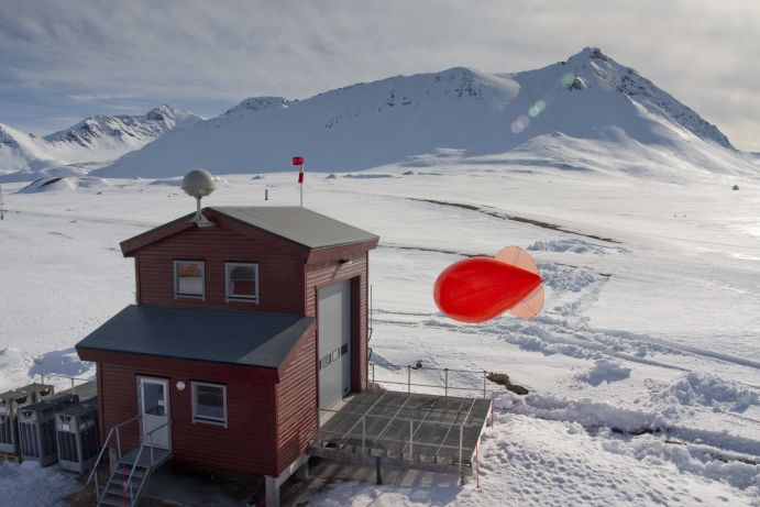 Ballonfüllhalle mit Fesselballon Die Atmosphärenforscher des Alfred-Wegener-Instituts nennen ihn „Miss Piggy“: Der rote Fesselballon kommt regelmäßig in mehrwöchigen Messkampagnen zum Einsatz. An einem 1,5 Kilometer Seil können Forscher mehrere Sonden in Reihe anbringen oder nacheinander Messsonden hoch und wieder runter lassen. Mit hoher zeitlicher und räumlicher Auflösung können sie so die spezielle Dynamik der arktischen Grenzschicht in der Umgebung von Gletschern und Bergen untersuchen - und noch nicht ausreichend verstandene Prozesse in der arktischen Atmosphäre besser abbilden. Das BMBF kooperiert über das AWI in der bilateralen Zusammenarbeit mit den arktischen Anrainern und anderen Staaten. Wichtige Partner sind hier Norwegen, Frankreich, Dänemark, Island, die USA, Japan, Kanada sowie Russland und China. Bundesforschungsministerin Wanka besuchte auf ihrer Arktisreise im April 2015 neben der AWIPEV-Station weitere deutsche und internationale Forschungseinrichtungen auf dem von Norwegen verwalteten arktischen Inselarchipel. Weitere Informationen zur Reise erhalten Sie hier.Ort: Ny-Ålesund, Spitzbergen (2010).