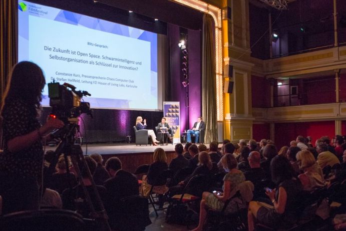 Impressionen vom Festivalabend des zweiten Foresight Filmfestivals. Blitzgespräch zur Kategorie "Die Zukunft ist Open Space" Noch bis 15. August 2017 ruft das Foresight Filmfestival (Nachwuchs-)Forschende, Filmschaffende und Projektentwickler*innen dazu auf Zukunftsvisionen in Form kurzer Filme zu visualisieren und zum Wettbewerb einzureichen. Im Zentrum des Foresight Filmfestivals steht der interdisziplinäre Dialog um Fragestellungen, die sowohl technologische Innovationen als auch gesellschaftliche Bedarfe reflektieren. Es geht um Wecheselwirkungen, Chancen und Risiken, die sich daraus ergeben. Zusammengefasst, sucht das Foresight Festival nach filmerischen Antworten auf die Frage: Wie wollen und werden wir in Zukunft leben? Veranstalter des Firesight Festivals ist der gemeinnützige Verein science2public.