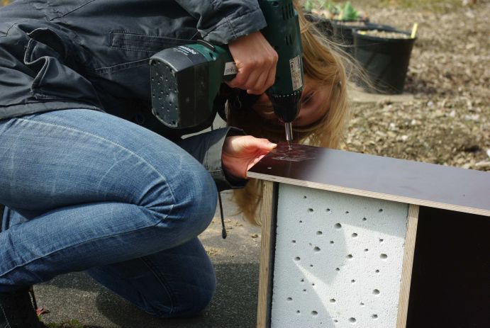 Bildbeschreibung: Die letzte aufgeschraubte Holzplatte dient dem Wildbienenhotel als Dach und schütz seine baldigen Bewohner vor Regen.  Im Rahmen des vom Bundesministerium für Bildung und Forschung geförderten "Wissenschaftsjahrs 2012&nbsp; – Zukunftsprojekt Erde" fand des Wildbienenprojekt "Erst bauen, dann schauen" statt. Von Mai bis Ende August konnten Fotos von selbstgebauten Nistplätzen für Wildbienen für den Wettbewerb zum originellste Wildbienenhotel eingesendet werden.  FONA war inhaltlicher Kooperationspartner des Wissenschaftsjahrs 2012.