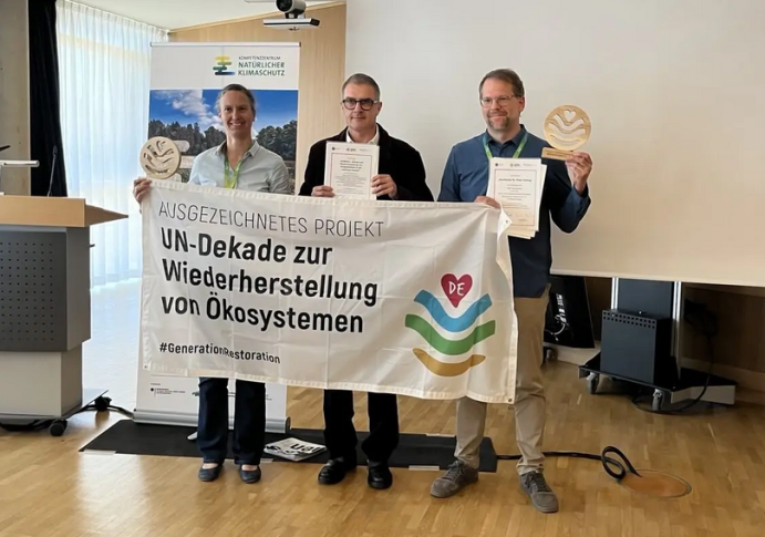 Jeweils stellvertretend für das gesamte Projektkonsortium nahmen Maike Paul (Projekt „Seastore“, Universität Hannover) und Jannes Fröhlich (Projekt „Sandküste“, WWF) die Urkunde sowie die Holztrophäe entgegen.