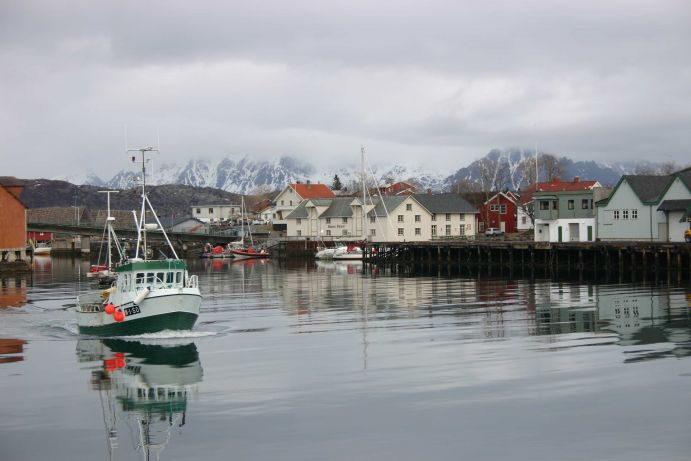 Ein Fischerboot in verlässt einen Hafen auf den Lofoten, einer eine Inselgruppe vor der Küste Norwegens, bestehend aus etwa 80 Inseln.