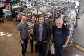 Das Forscherteam Tobias L&ouml;ffler, Alan Savan, Alfred Ludwig und Wolfgang Schuhmann (von links) vor der kombinatorischen Sputteranlage, in der die Nanopartikelbibliotheken hergestellt wurden.