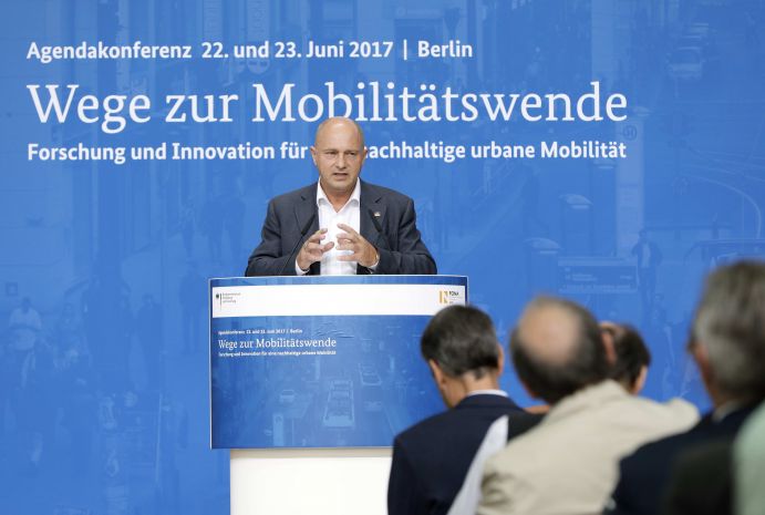 Rainer Bomba (Staatssekretär im BMVI) auf der Agendakonferenz "Wege zur Mobilitätswende" am 22. und 23. Juni 2017 in Berlin Mobilität und urbaner Verkehr befinden sich derzeit in einem dynamischen Wandel. In den Städten entstehen zum einen vielfältige neue Mobilitätsdienstleistungen und Verkehrsangebote, zum anderen verändern sich Mobilitätsmuster und Rahmenbedingungen der Mobilität. Dieser Wandel der Mobilitätswelt erfordert eine verstärkte Einbindung der Forschung, um diesen Wandel mit zu gestalten. Das Bundesministerium für Bildung und Forschung (BMBF) führt daher im Jahr 2017 einen Agendaprozess „Nachhaltige urbane Mobilität" durch. Dieser erfolgt unter Mitwirkung des Bundesministeriums für Verkehr und digitale Infrastruktur (BMVI).
Im Rahmen dieses Prozesses diskutierten 300 Expertinnen und Experten aus Wissenschaft, Wirtschaft, Politik und Zivilgesellschaft auf der "Agendakonferenz: Wege zur Mobilitätswende" über Forschungs- und Umsetzungsbedarfe für eine nachhaltige Entwicklung von Mobilität in Städten.