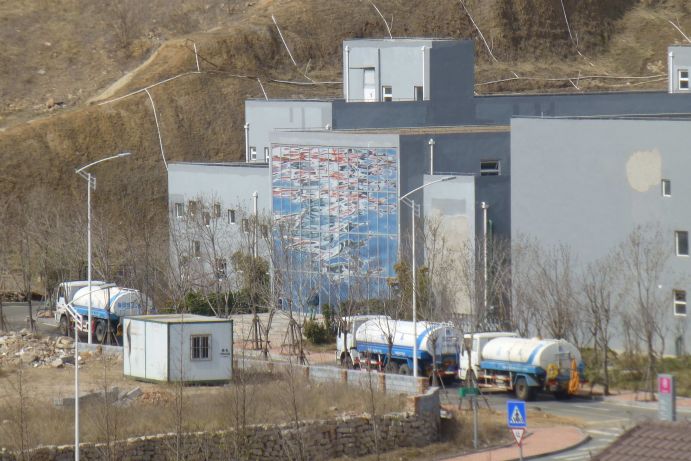 SEMIZENTRAL-Anlage in Qingdao, China: Tankwagen holen aufbereitetes Abwasser ab, welches in dem Wassermangelgebiet zur Bewässerung von öffentlichen Grünanlagen genutzt wird.
Das Foto zeigt die SEMIZENTRAL-Anlage, das weltweit erste semizentralen Wasserver- und –entsorgungszentrum, welche ein wichtiger Teilerfolg der über 10-jährigen Forschungs- und Entwicklungsarbeit des Verbundprojekts SEMIZENTRAL ist. Das Verbundprojekt SEMIZENTRAL ist Teil des „Forschungs- und Innovationsprogramms Sauberes Wasser“, das in Zusammenarbeit zwischen der Volksrepublik China und der Bundesrepublik Deutschland entstanden ist. Finanziert wird das Programm vom Ministerium für Wissenschaft und Technologie (MoST) der VR China und dem Bundesministerium für Bildung und Forschung (BMBF) im Rahmen der Wasserforschung, die einen Schwerpunkt der Forschung für Nachhaltige Entwicklung (FONA) bildet. Das Programm „Sauberes Wasser“ deckt Inhalte der Wasserversorgung, Abwasserbehandlung, dem Schutz der natürlichen Wasserressourcen und der sauberen industriellen Produktion ab. Zur erfolgreichen Durchführung unterstützt ein Projektbüro seit 2012 an der Tongji Universität Shanghai das Projekt. 