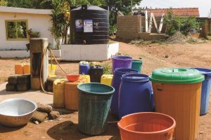 Wassertank und Wasserbehälter in Accra, Ghana. Bunte Eimer stehen vor einem Wassertank. (WaterPower, Universität Trier)