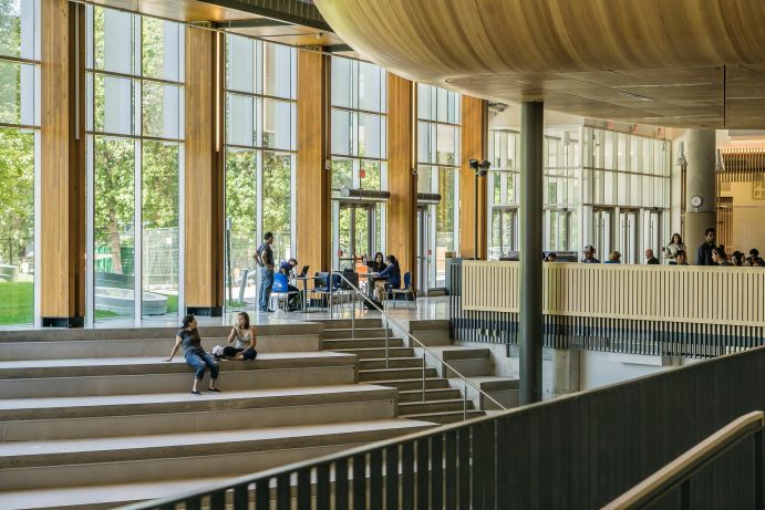 Studierende sitzen in einem hellen Foyer und unterhalten sich