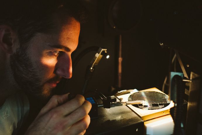 Tandemsolarzelle aus Silicium und III-V-Halbleitern ermöglicht eine deutlich bessere Ausnutzung des Sonnenspektrums als heutige Standardsolarzellen. Ein Wissenschaftler betrachtet eine Tandemsolarzelle unter einer Lichtquelle
