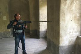 Ein Mann Bohrt mit einem 90cm langen Bohrer ein Loch in eine Wand (Institut für Bauklimatik, TU Dresden)