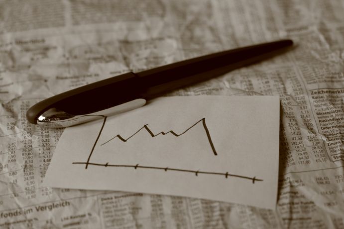 Börsenkurs Talfahrt - Plötzlich einbrechende Aktienkurse sind ein prominentes Merkmal von Finanzkrisen und Grund, sich Gedanken zu machen, ob unser krisengeschütteltes Finanzsystem belastbar ist, die Transformation zur emissionsarmen Wirtschaft zu finanzieren. Kugelschreiber zeichnet Kurve zu abfallendem Börsenkurs