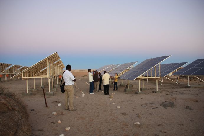 Aufbau von dezentralen, für kleinere Gebiete geeignete Mini-Stromnetze, die die ländliche Bevölkerung mit Energie versorgen. Photovoltaikmodule auf Ständer in einer Sand- und Steinwüste.