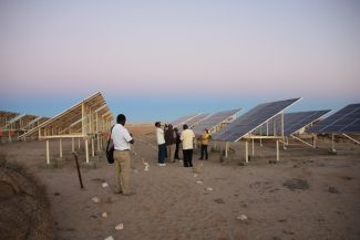 Photovoltaikmodule auf Ständer in einer Sand- und Steinwüste.