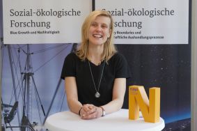 Prof. Dr. Melanie Jaeger-Erben steht an einem Tisch.