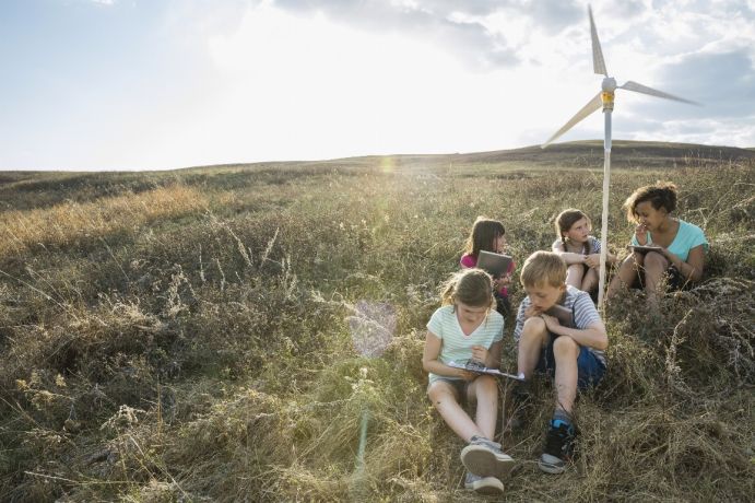 Im Rahmen des Aktonsplans "Natürlich. Digital. Nachhaltig." setzt sich das BMBF dafür ein, die Vermittlung nachhaltiger und digitaler Kompetenzen in die Aus- und Fortbildungsordnungen aufzunehmen. Schulkinder diskutieren über das Modell eines Windrades