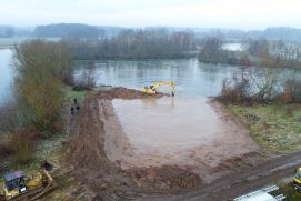 Ein Baggersee wird am Ufer mit Erde aufgeschüttet, um Flachwasserzonen für Pfnazen und Tiere zu schaffen.