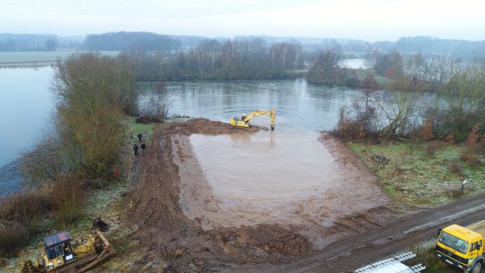 Ein Baggersee wird am Ufer mit Erde aufgeschüttet, um Flachwasserzonen für Pfnazen und Tiere zu schaffen.