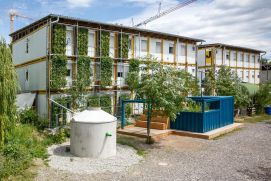 Zukunftsstadt - Wohncontainer in Stuttgart mit begrünten Wänden und einer Zisterne davor.