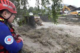 Ein Mann von der Wasserwacht schaut auf einen reißenden Fluss nach Starkregen in Garmisch-Partenkirchen.