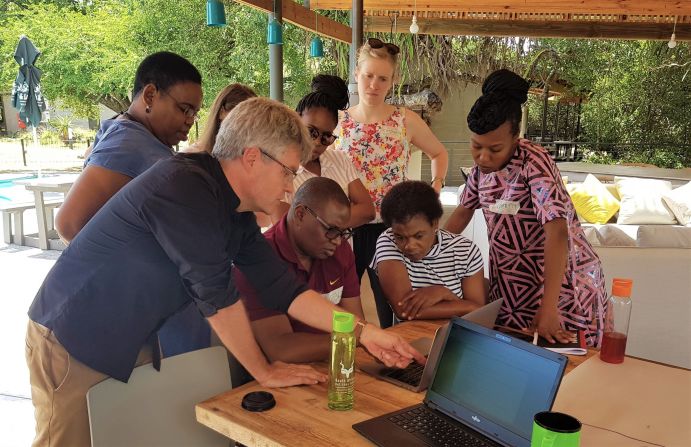 Prof. Thomas Clemen (HAW Hamburg) demonstriert Klimaszenarien auf dem EMS Africa-Bushbuckridge Local Municipality Stakeholder-Workshop im März 2020. Ein Wissenschaftler zeigt einer kleinen Gruppe von Forschenden an einem Laptop Forschungsergebnisse.