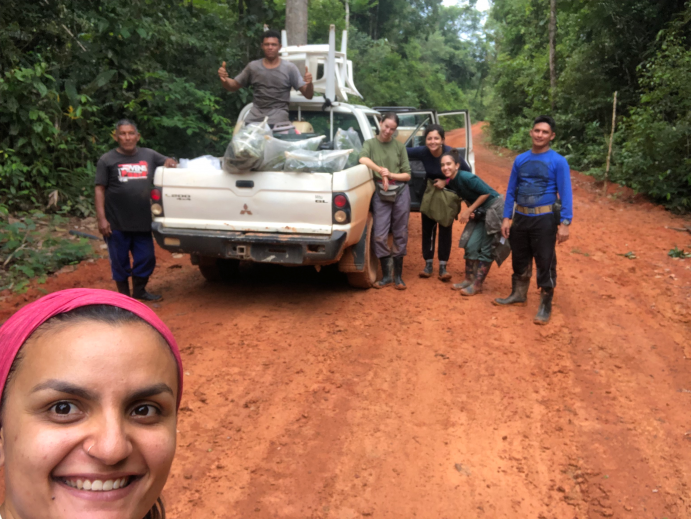 Dr. Eliane Gomes-Alves vom Max-Planck-Institut für Biogeochemie forscht seit 2015 für das ATTO Projekt. Tag der Tropenwälder - Selfie einer Forscherin im Amazonas mit einem Pick-up Wagen und einer Gruppe von Menschen im Hintergrund.