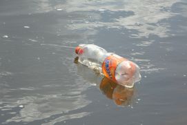 Plastikflasche treibt in trübem Flusswasser