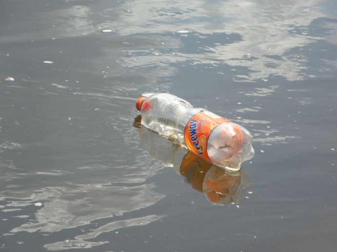 Plastikflasche treibt in trübem Flusswasser