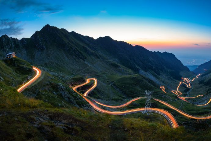 Das Projekt H2-Kompass erstellt Handlungsoptionen und Anwendungsszenarien für Wasserstoff. Berglandschaft mit Serpentinenstraßen, die durch lange Belichtung die Rückleuchten und Scheinwerfer fahrender Autos als Streifen zeigen.