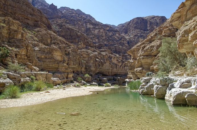 Das Flussbett Wadi Shab im Oman; das Wadi versorgt Siedlungen und Landwirtschaft mit Wasser. Trockene Wüstenlandschaft mit Flussbett