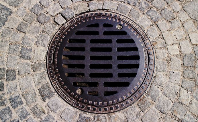 Wasser-Extremereignissen wie Starkregen und Überschwemmungen stellen eine große Belastung für städtische Entwässerungsinfrastrukturen dar Luftaufnahme eines Gullydeckels