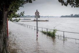 Überflutete Flussufer mit Hochwasserwarnschild