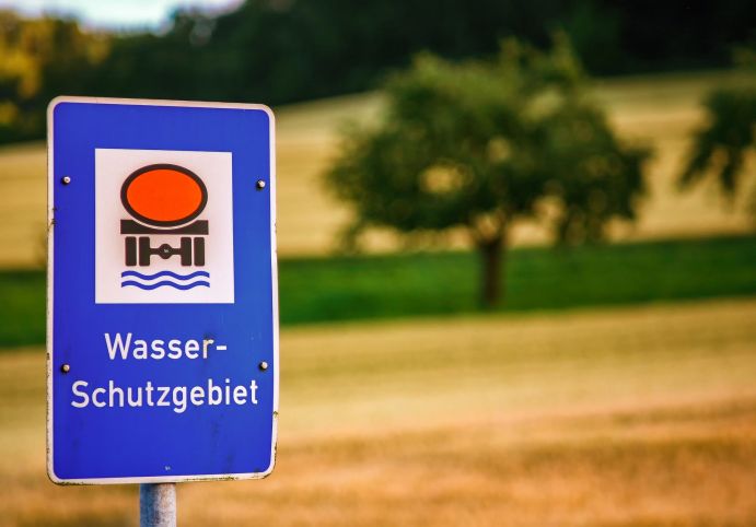 Schild mit Hinweis Wasserschutzgebiet vor verschwommener Landschaft