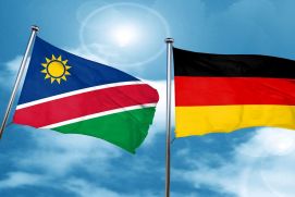 The picture shows the Namibian and German flags against a slightly cloudy blue sky.