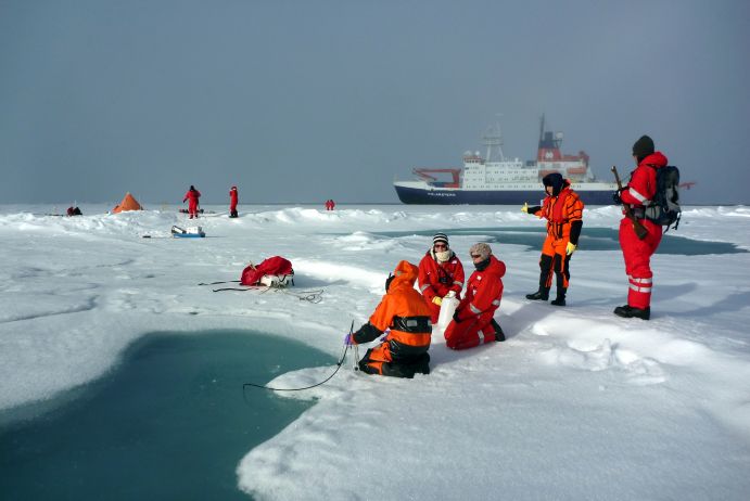 Ein Expeditionsteam der POLARSTERN nimmt Messungen an einem Schmelztümpel im Arktischen Ozean vor. 