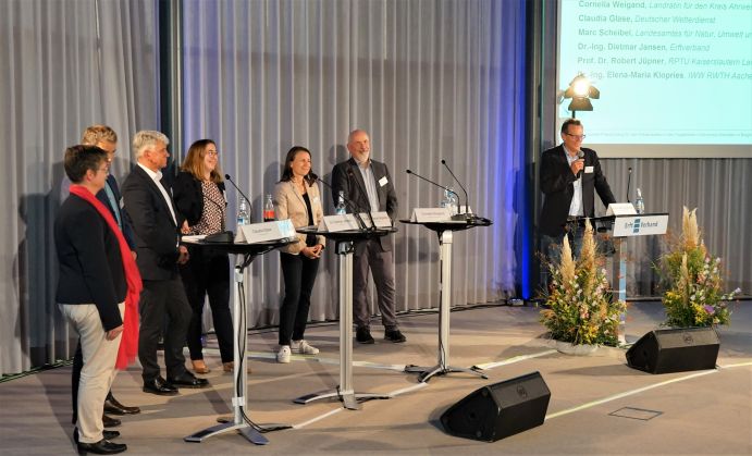 Podiumsdiskussion (v.l.n.r.): Claudia Glase vom Deutschen Wetterdienst, Marc Scheibel vom Landesamt für Natur, Umwelt und Verbraucherschutz NRW, Dr.-Ing. Dietmar Jansen vom Erftverband, Dr.-Ing. Elena-Maria Klopries von der RWTH Aachen, Cornelia Weigand, Landrätin für den Kreis Ahrweiler und Prof. Dr. Robert Jüpner von der RPTU Kaiserslautern-Landau. Moderation Prof. Dr.-Ing. Jörn Birkmann 