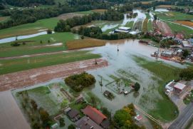 Drohnenaufnahme eines überfluteten Gebirgstals, in der Nähe von Haushalten und Verkehrswegen. 