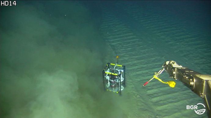 Auf dieser Aufnahme eines Unterwasserroboters ist eine Sedimentwolke zu sehen, die sich quer zu den Abbau-Spuren ausbreitet. Der mit Sensoren ausgestattete Mikroprofiler in der Bildmitte ist etwa so groß wie ein Reisekoffer. Auf dieser Aufnahme eines Unterwasserroboters ist eine Sedimentwolke zu sehen, die sich quer zu den Abbau-Spuren ausbreitet. Der mit Sensoren ausgestattete Mikroprofiler in der Bildmitte ist etwa so groß wie ein Reisekoffer.